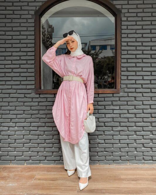 Wanita Indonesia mengenakan kemeja merah muda besar dan jilbab putih yang disebut jilbab.